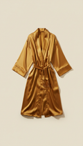 A luxury lounge robe in a rich Gold color, centered on a Cornsilk background. The soft, even illumination enhances the...